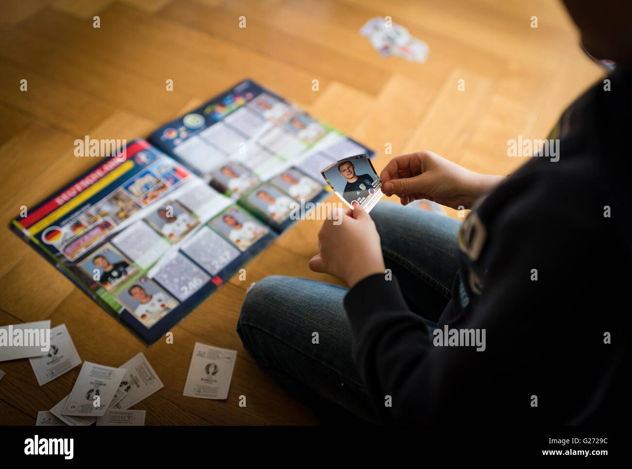 Ein 8 Jahre alter Junge ist in seinem Aufkleber Sammlung Sammelalbum UEFA Euro 2016 Panini Fußball-Sammelkarten einfügen. Stockfoto