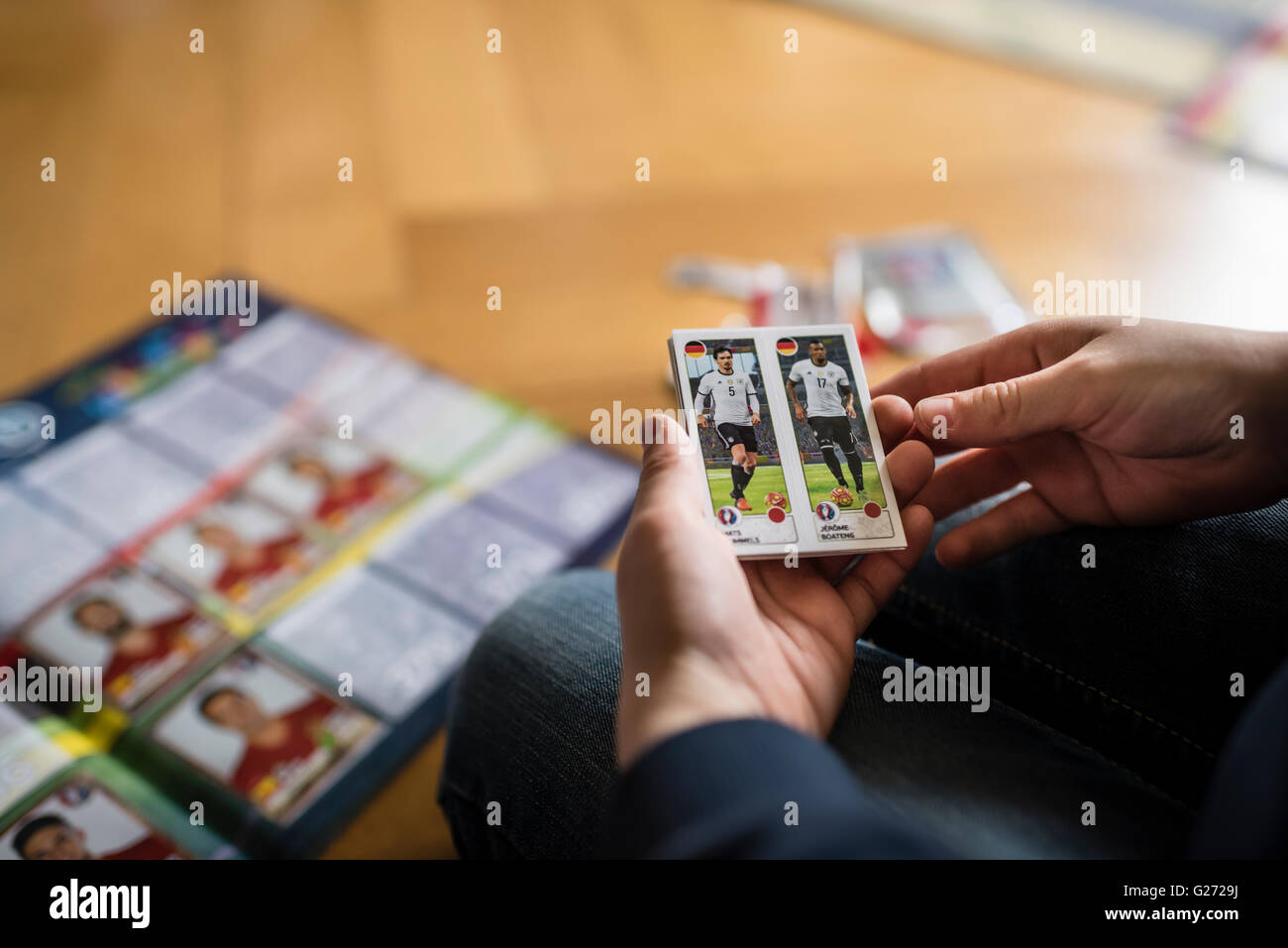 Ein 8 Jahre alter Junge ist in seinem Aufkleber Sammlung Sammelalbum UEFA Euro 2016 Panini Fußball-Sammelkarten einfügen. Stockfoto