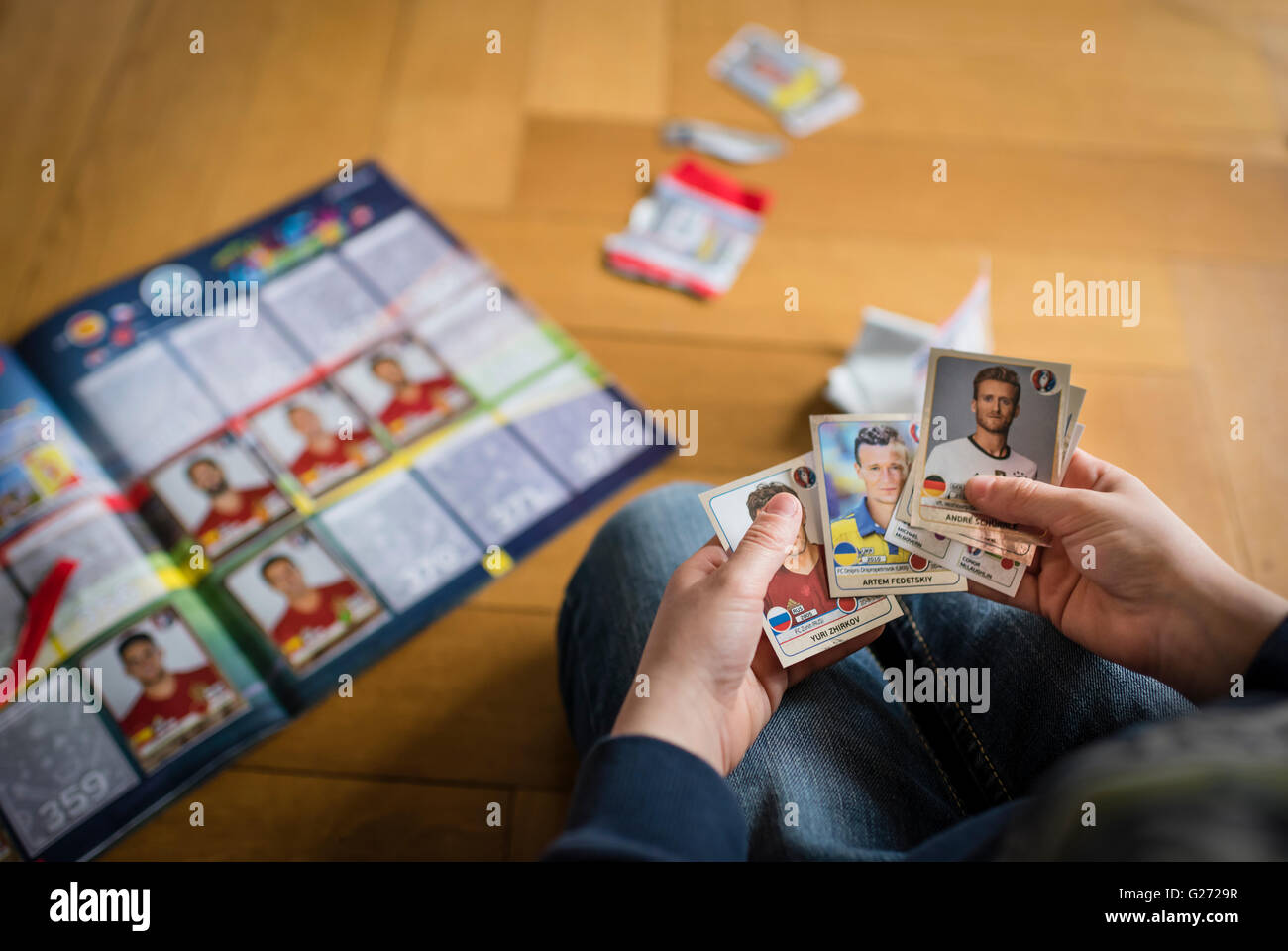 Ein 8 Jahre alter Junge ist in seinem Aufkleber Sammlung Sammelalbum UEFA Euro 2016 Panini Fußball-Sammelkarten einfügen. Stockfoto