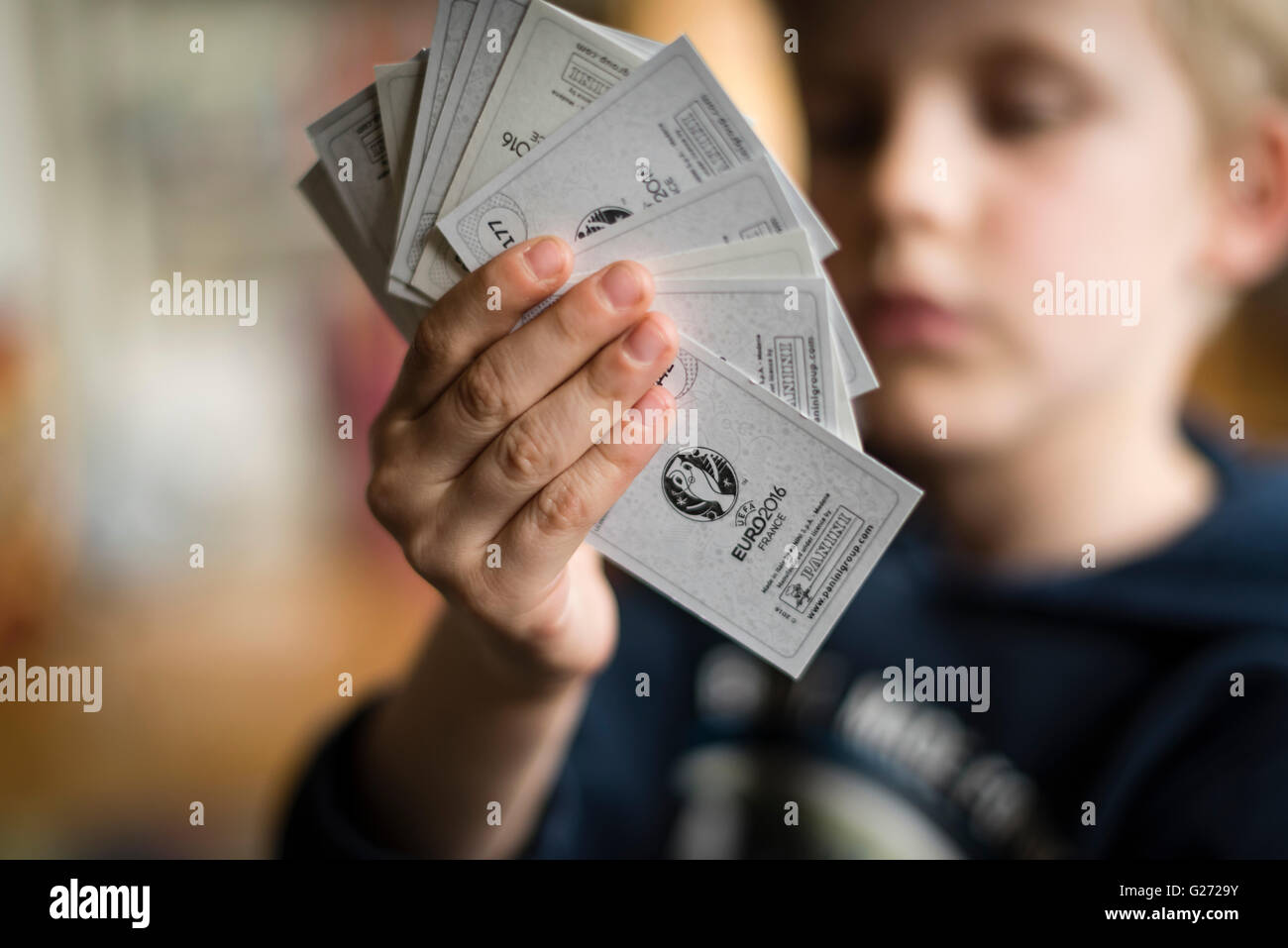 Ein 8 Jahre alter Junge zeigt seine Panini Fußball-Sammelkarten vor in seinem Aufkleber Sammlung Sammelalbum einfügen. Stockfoto