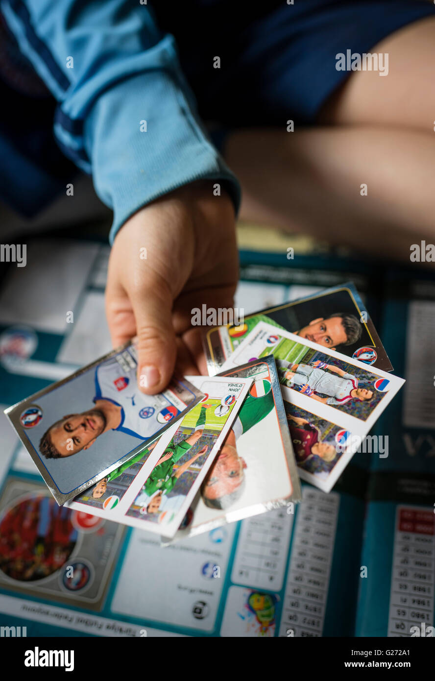 Ein 8 Jahre alter Junge zeigt seine Panini Fußball-Sammelkarten vor in seinem Aufkleber Sammlung Sammelalbum einfügen. Stockfoto