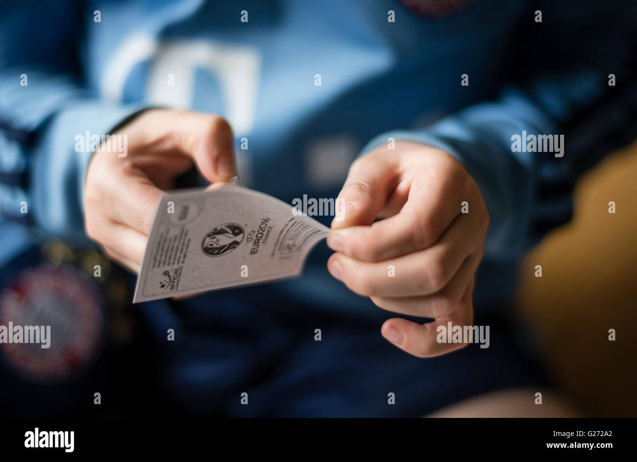 Ein 8 Jahre alter Junge entfernen die Rückseite von einem Panini Fußball Sticker vor dem Einfügen in seinem Aufkleber Sammlung Sammelalbum Stockfoto