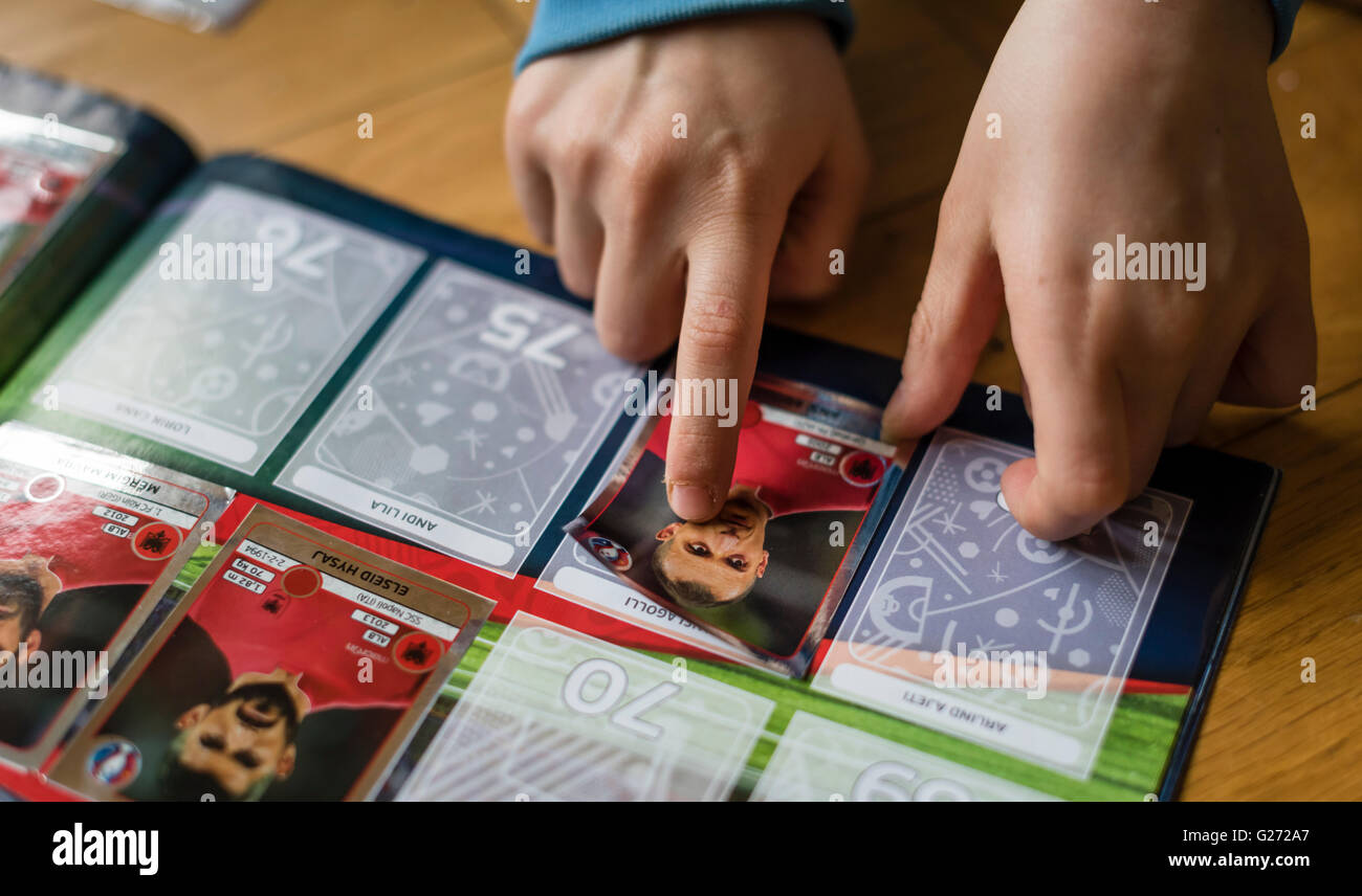 Ein 8 Jahre alter Junge ist in seinem Aufkleber Sammlung Sammelalbum UEFA Euro 2016 Panini Fußball-Sammelkarten einfügen. Stockfoto