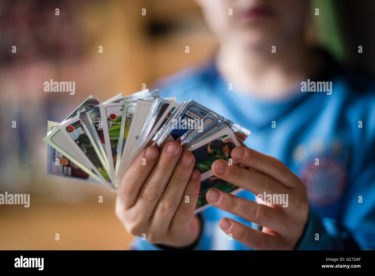 Ein 8 Jahre alter Junge zeigt seine Panini Fußball-Sammelkarten vor in seinem Aufkleber Sammlung Sammelalbum einfügen. Stockfoto