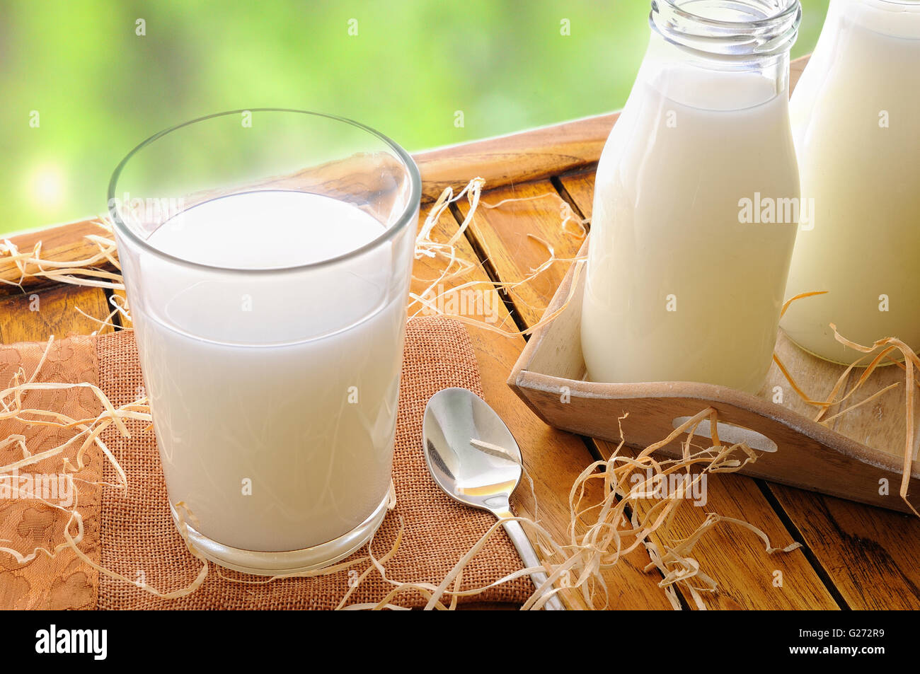 Glas Milch auf einem Tisch mit zwei Flaschen Milch auf dem Feld Stockfoto