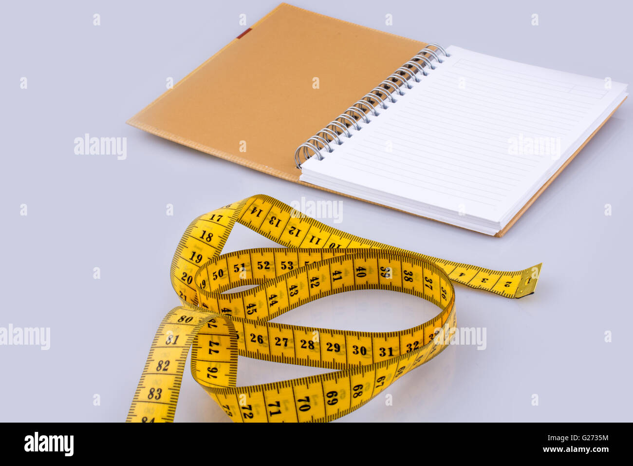 Maßband in der Nähe von einem Notebook auf weißem Hintergrund Stockfoto