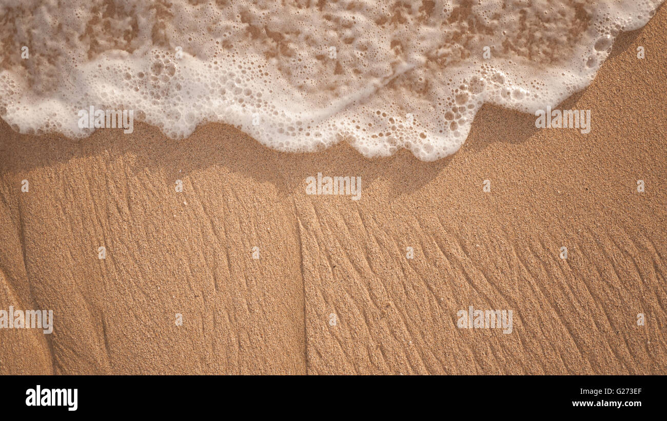 Nahaufnahme der Ozean, Wellen, Strand bei Sonnenuntergang oder Dämmerung in Hawaii. Welle über sandigen Strand waschen. Stockfoto