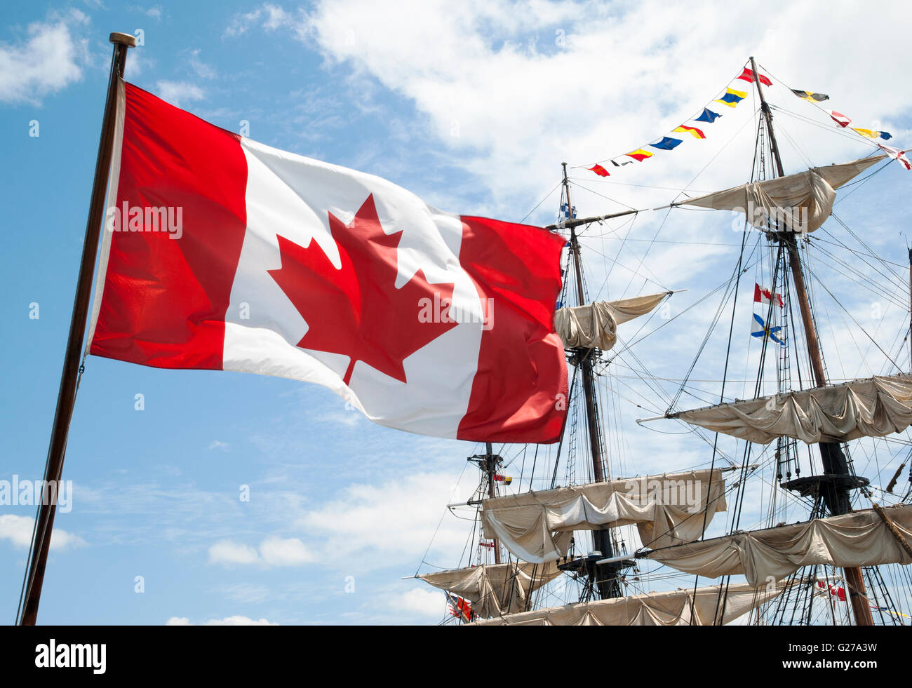 Die Nahaufnahme der kanadischen Flagge mit historischen Schiffsmasten im Hintergrund (Halifax, Kanada). Stockfoto
