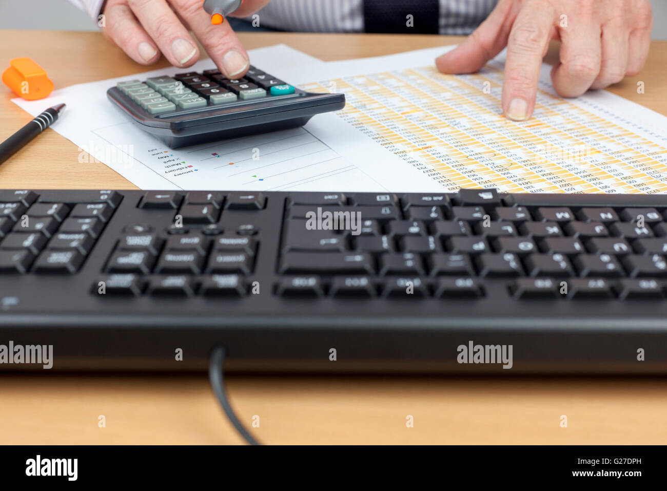 Finanziellen Arbeitskraft beschäftigt an seinem Schreibtisch mit einem Rechner und Überprüfung einer Tabellenkalkulation Stockfoto