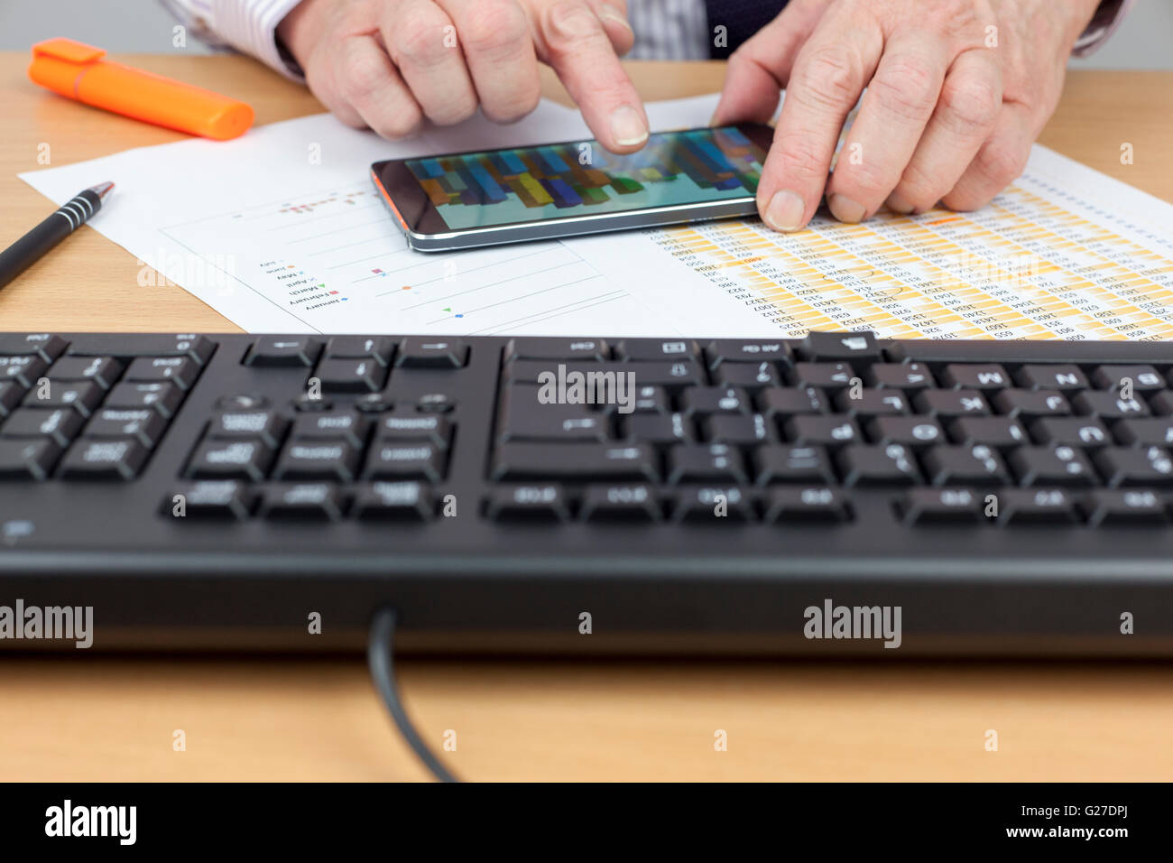 Kapitalbilanz beschäftigt an seinem Schreibtisch ein Balkendiagramm auf seinem Smartphone überprüfen Stockfoto