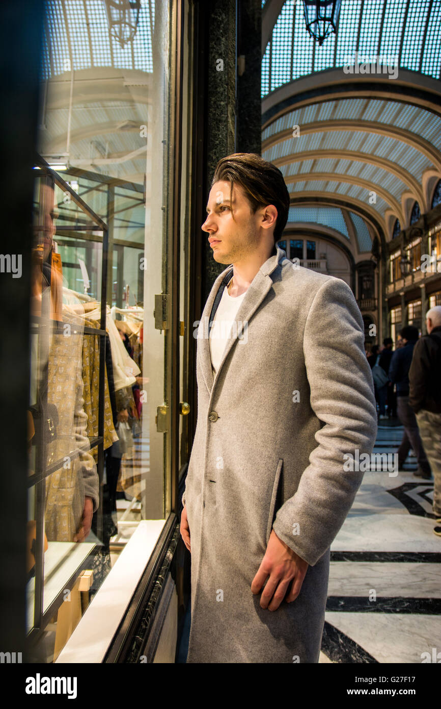 Hübscher junger Mann im schwarzen eleganten Anzug Blick auf Modeartikel in Glas-Fenster-Boutique an der High Street-Seite angezeigt. Stockfoto