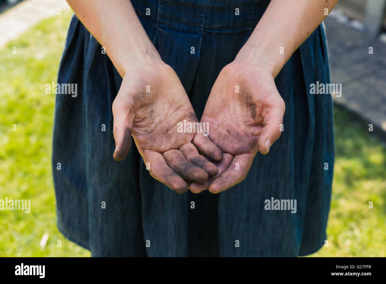 Eine junge Frau zeigt ihre schmutzigen Hände im Schmutz von Gärtnern bedeckt Stockfoto