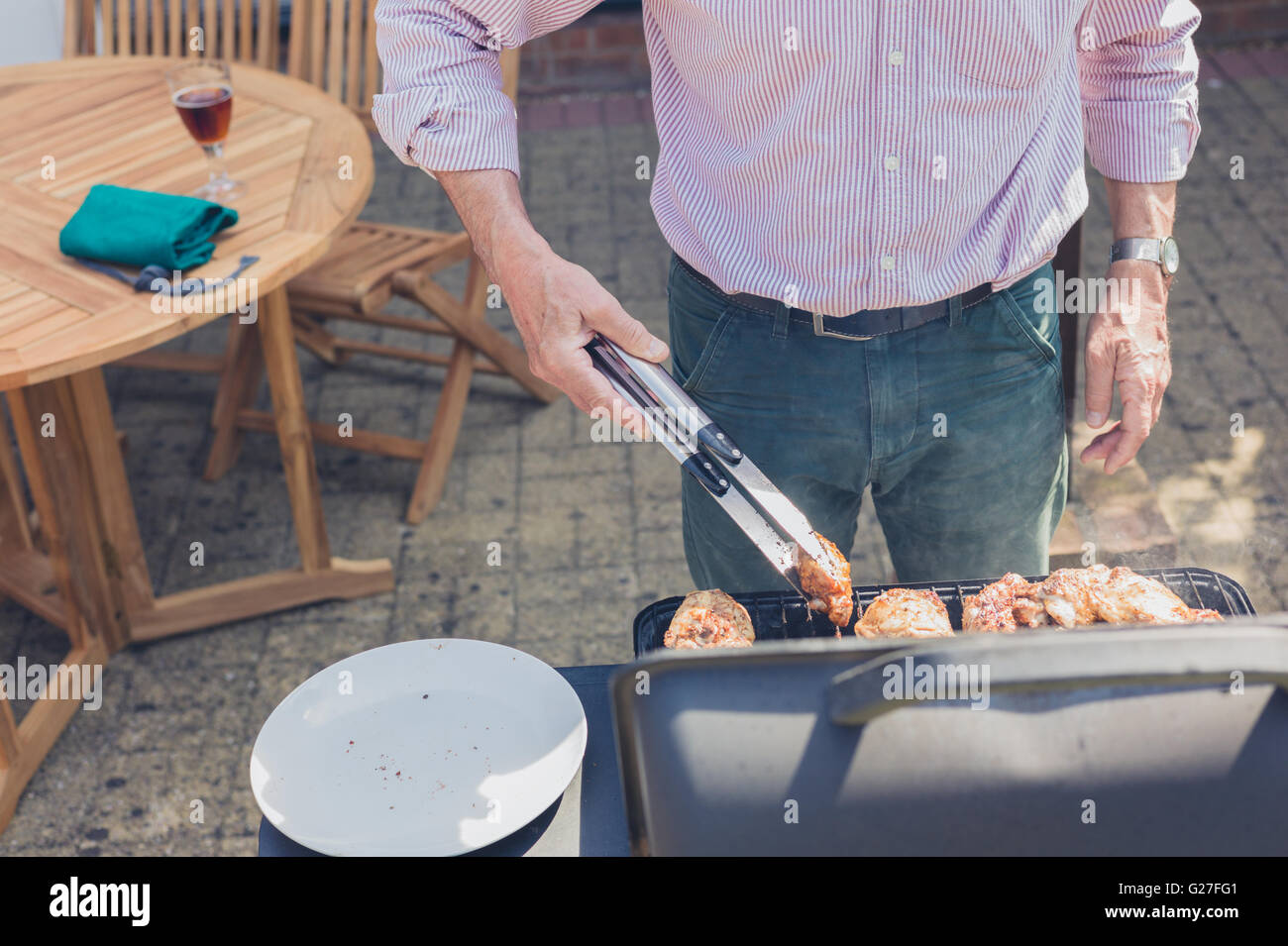 Ein älteren Mann besucht zu einer Grillparty im Garten an einem sonnigen Tag Stockfoto