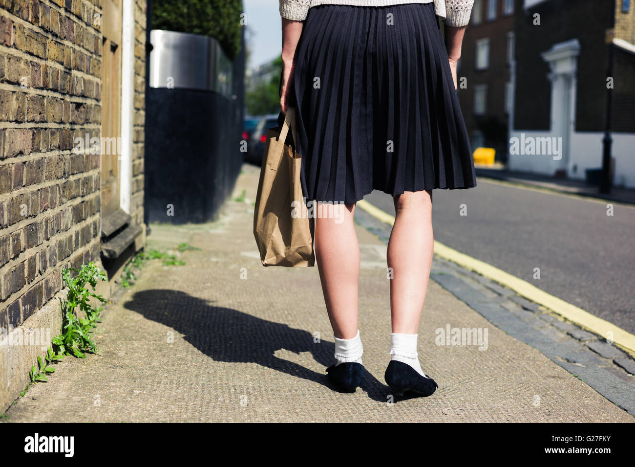 Eine junge Frau trägt einen Rock auf der Straße an einem sonnigen Tag Fuß Stockfoto