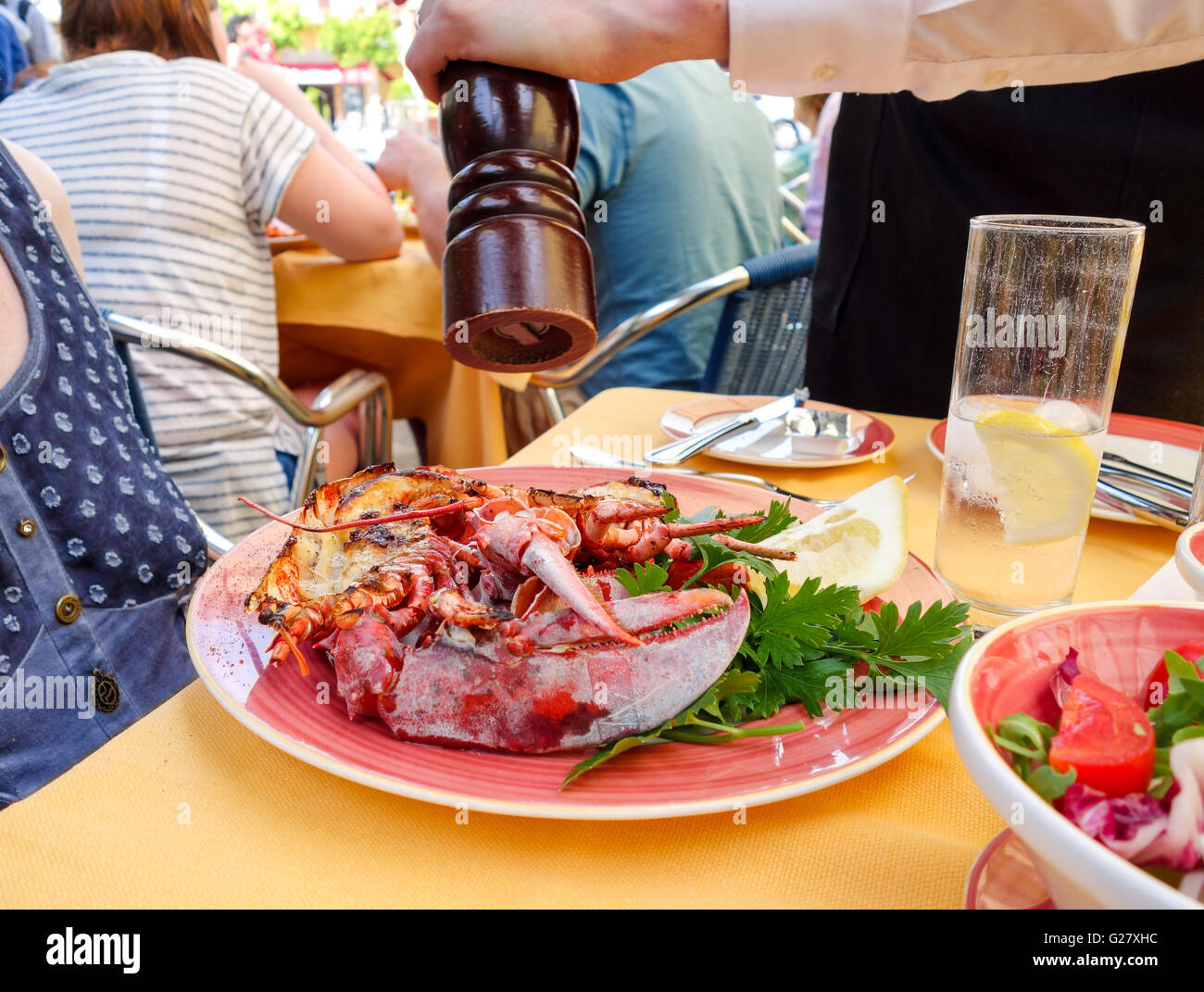 Ein Hummer wird bestreut mit schwarzem Pfeffer aus einer Pfeffermühle Abendessen außerhalb in einem Freiluft-Café-restaurant Stockfoto