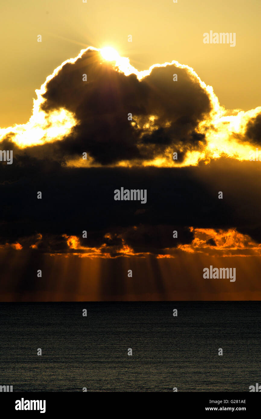 Strahlen der Sonne brach durch Wolken in orange Lichtstrahlen ins Meer stürzen Stockfoto