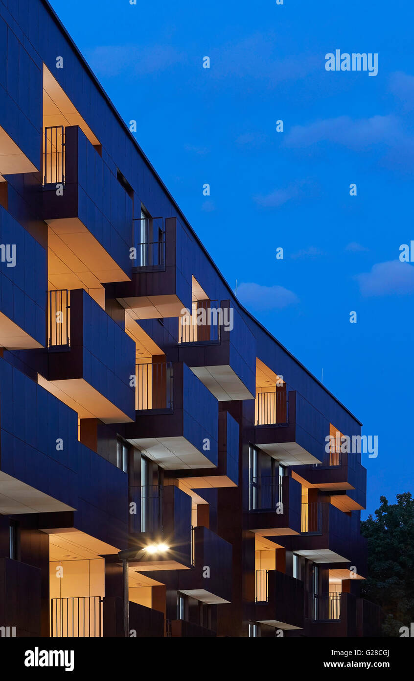 Fassade-Perspektive mit vorspringenden Balkonen und und Innenräume in der Nacht beleuchtet. Alpine Ort, Brent, London, Vereinigtes Königreich. Architekt: Ayre Chamberlain Gaunt, 2015. Stockfoto
