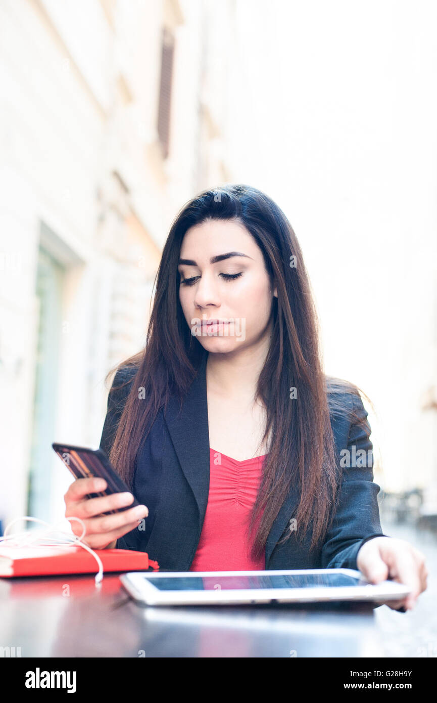 Junge Geschäftsfrau arbeiten mit Tablet und Handy an einem Tisch im Freien in der Stadt Stockfoto