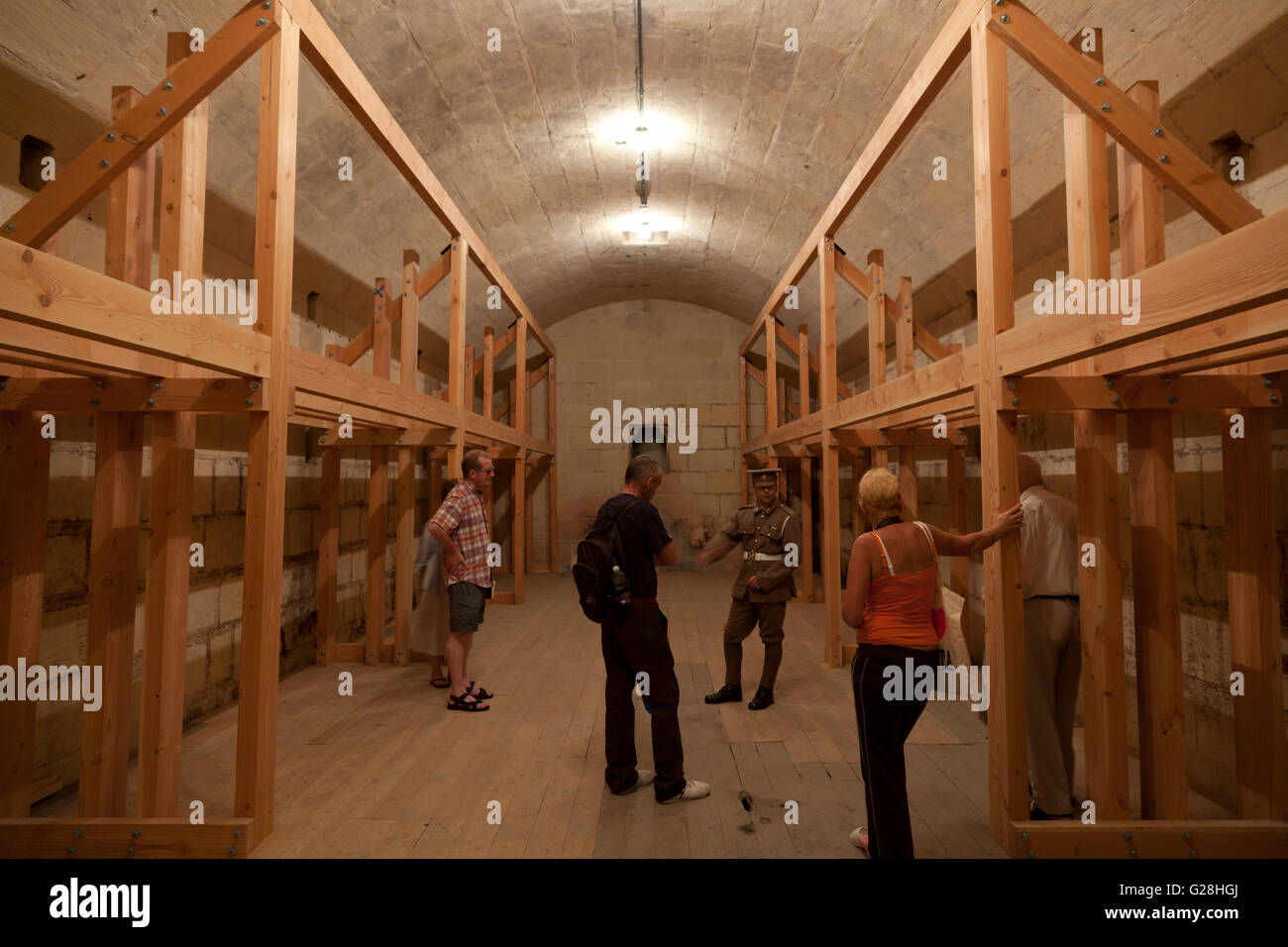 Ein Leitfaden in britischen militärischen Strapazen führt eine Gruppe von Besuchern innerhalb einer historischen Tonnengewölbe militärische Zeitschrift. Stockfoto