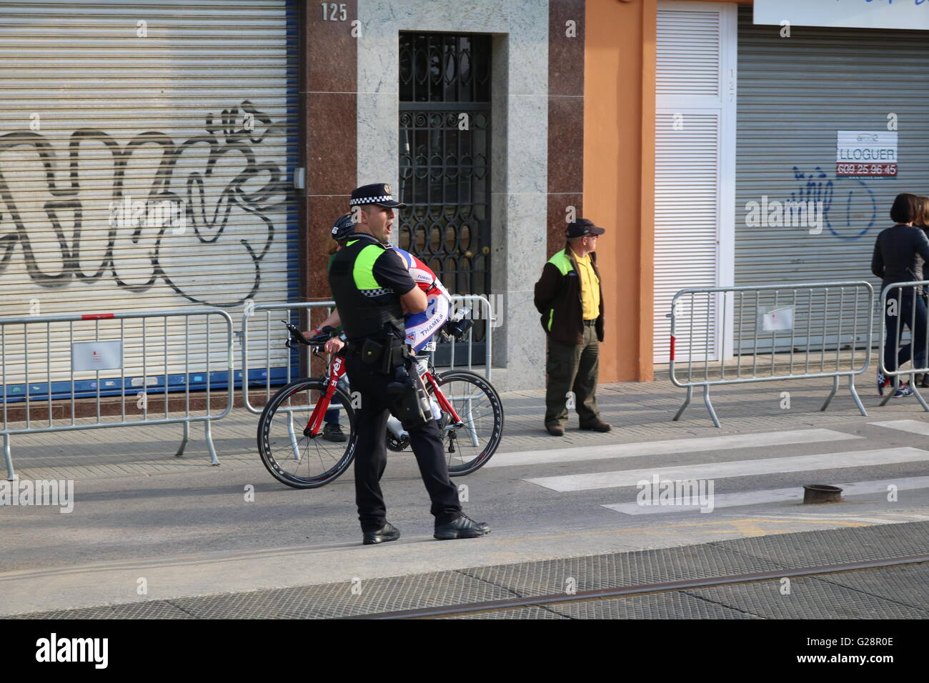 Ein Polizist gähnt, nachdem gerade Hunderte von Fahrrädern und Triathleten übergeben ihn an Ironman Barcelona 70.3 in Spanien. Stockfoto