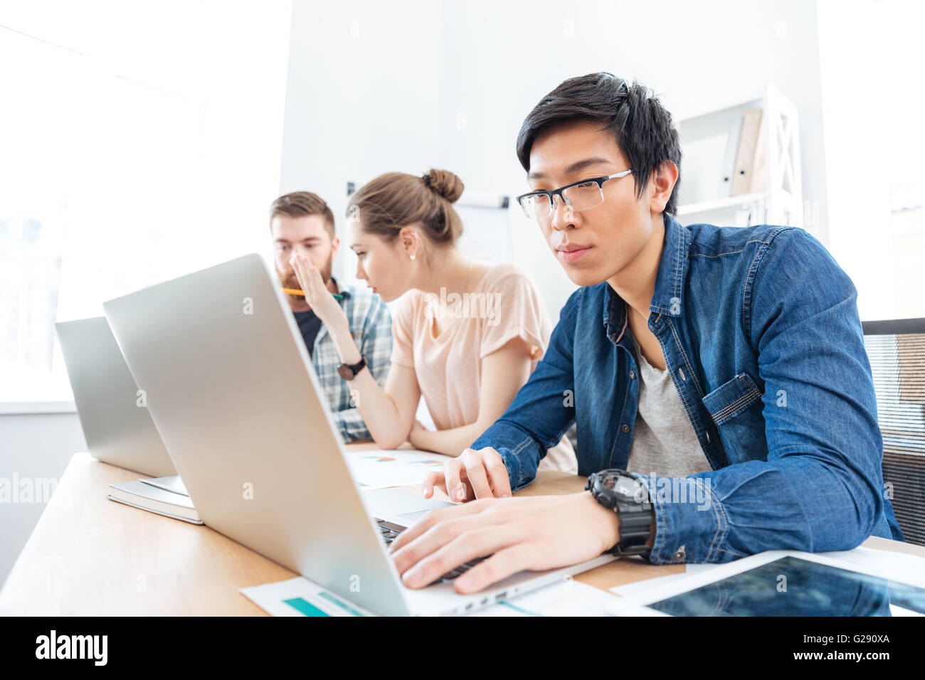 Drei konzentriert junge Geschäftsleute arbeiten im Büro mit laptops Stockfoto
