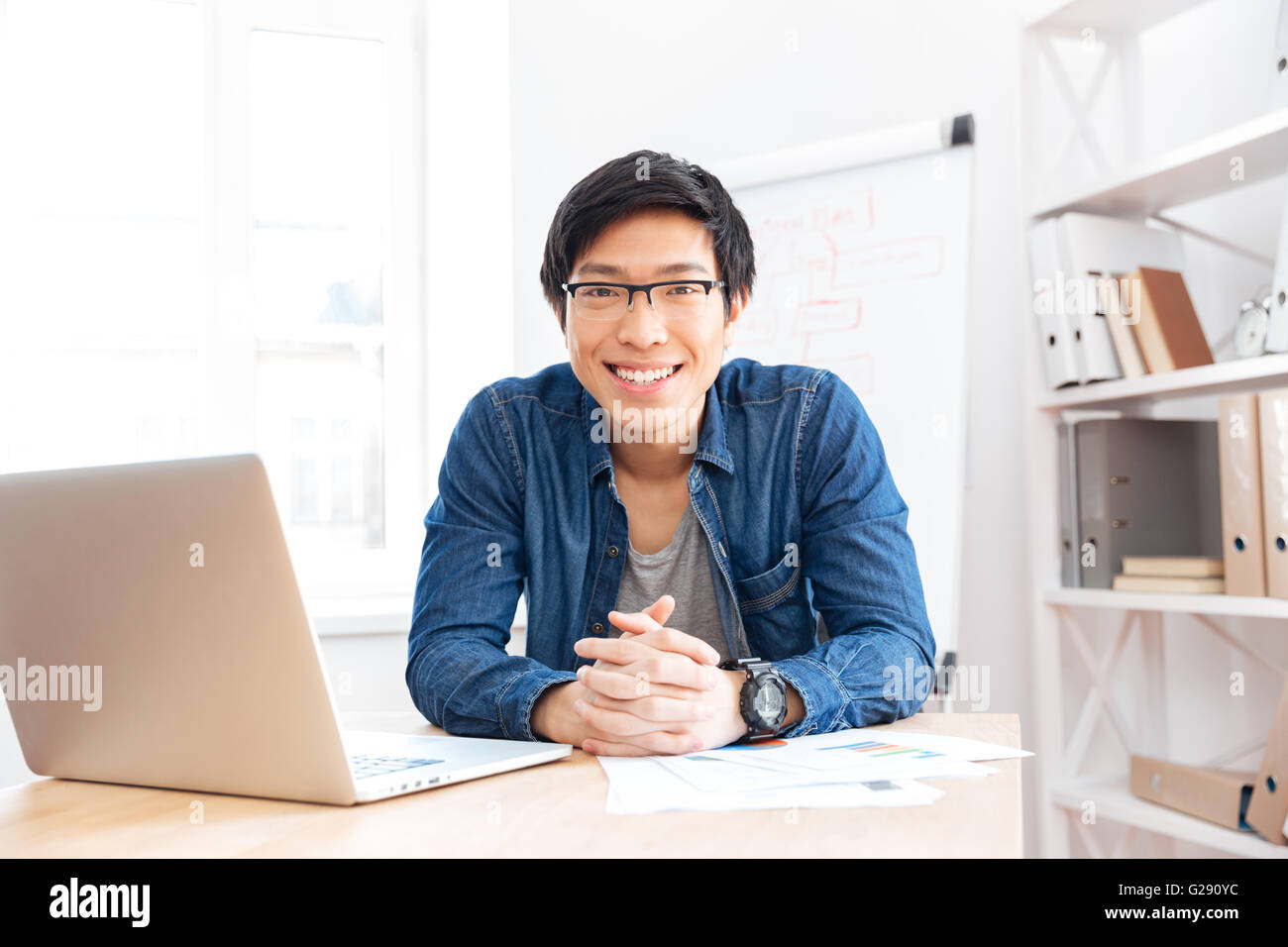 Porträt von fröhlich asiatischen Jungen Geschäftsmann arbeiten mit Laptop am Arbeitsplatz Stockfoto