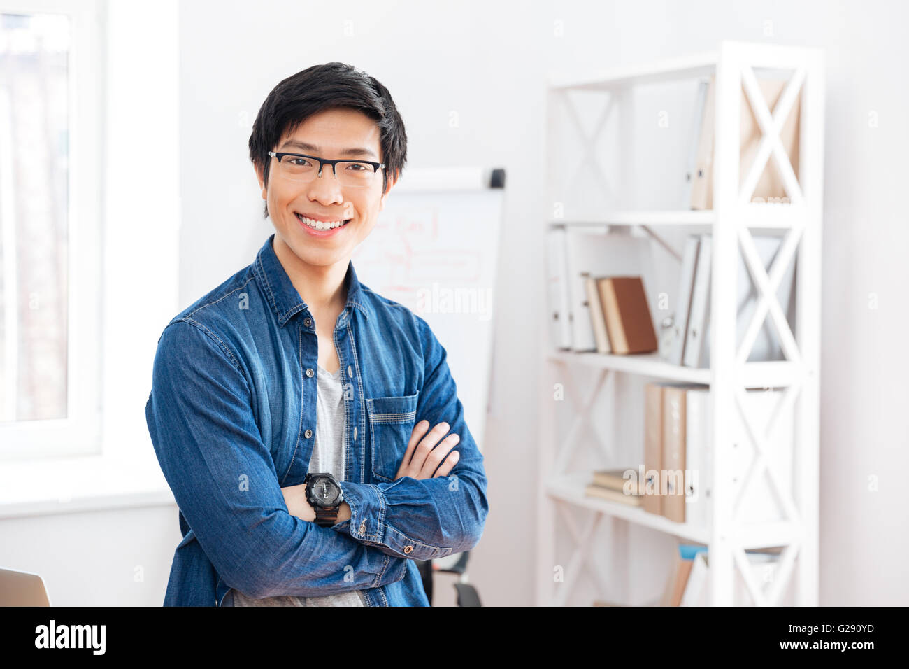 Glücklich schönen asiatischen junger Geschäftsmann stand mit verschränkten im Büro Stockfoto