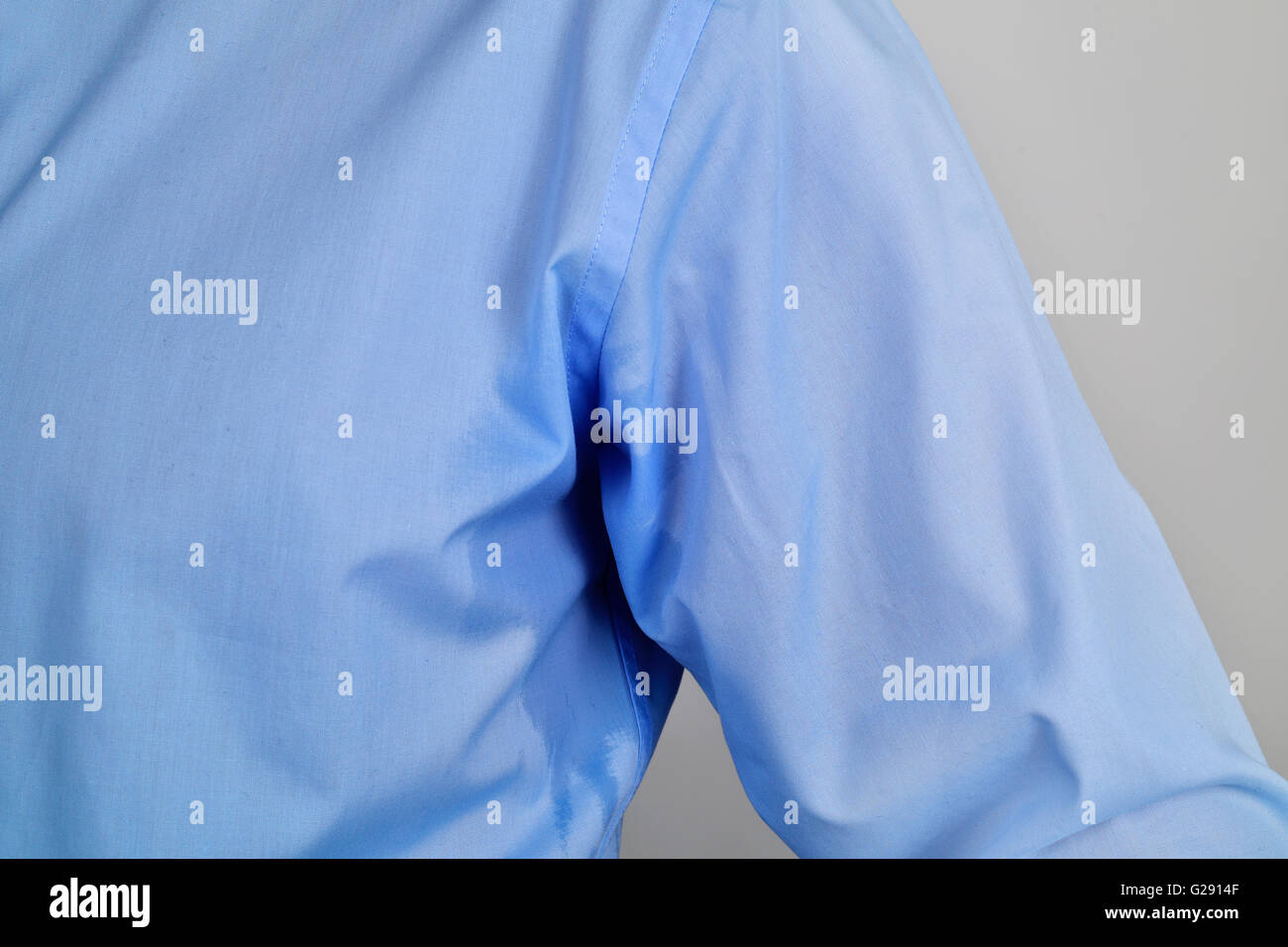 Nahaufnahme eines Mannes trägt ein blaues Hemd mit einem Schweiß-Fleck in seinem Unterarm Stockfoto