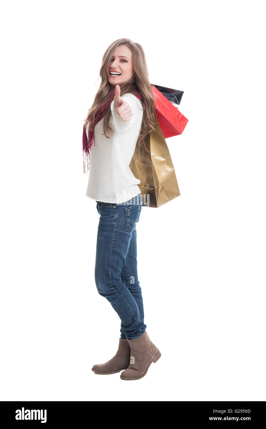 Shopping Mädchen zeigt Daumen oben und Einkaufstaschen über die Schulter zu halten Stockfoto