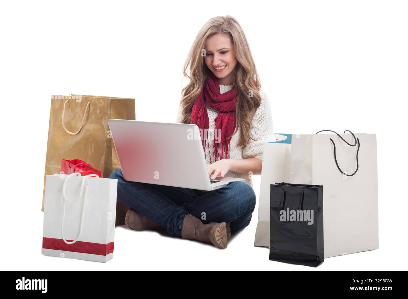 Frau mit Laptop und sitzen auf dem Boden mit Einkaufstüten online kaufen Stockfoto