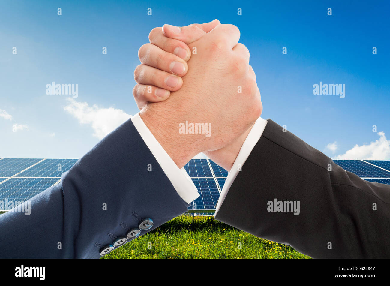 Unternehmer-Handshake als Teamarbeit auf Solarpower-Photovoltaik-Panel-Hintergrund. Erneuerbare Energien-Partnerschaftsabkommen Stockfoto