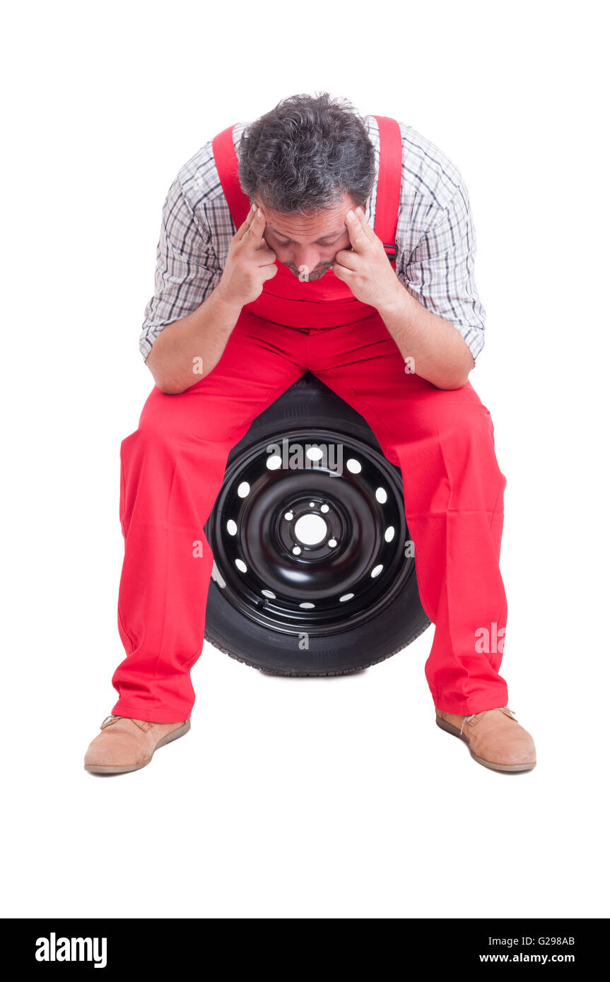 Müde Mechaniker seine Schläfen massiert, beim stillstehen auf einem Autoreifen Stockfoto