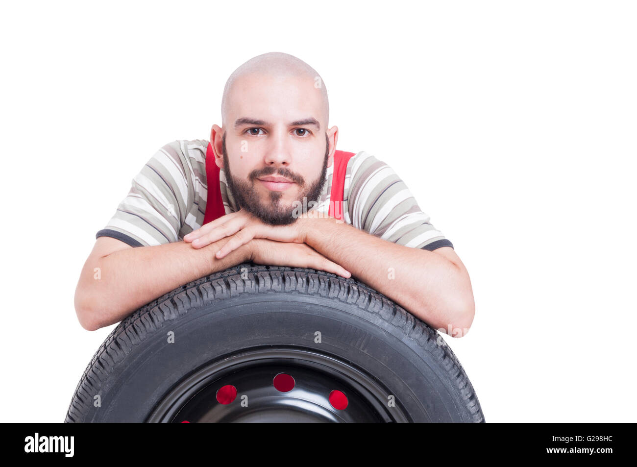 Art und freundliche junge Mechaniker ruht auf Auto-Rad Reifen isoliert auf weiss Stockfoto