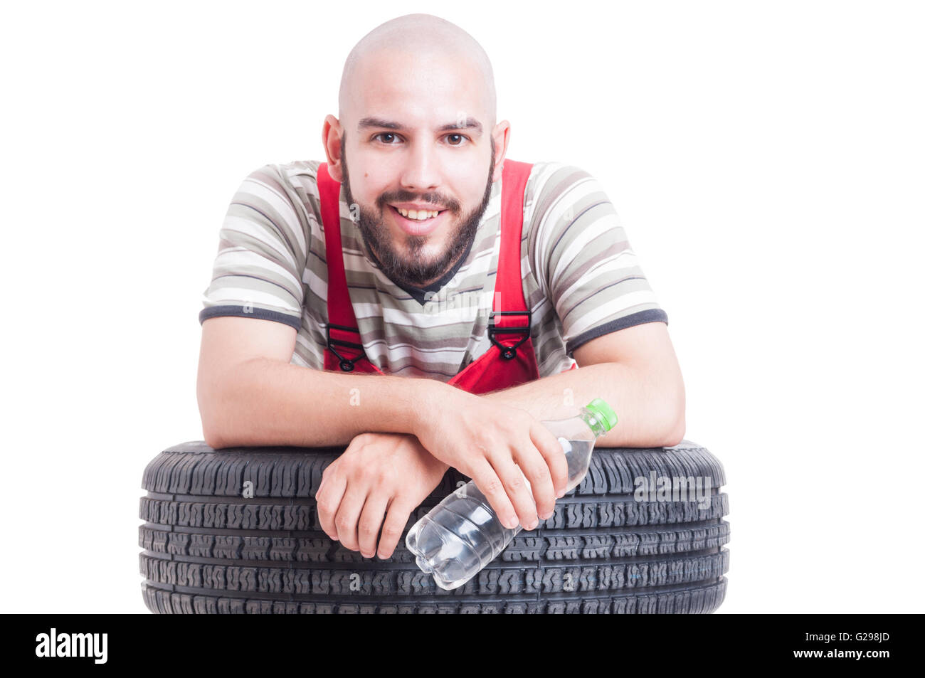 Lächelnde Mechaniker hält eine Flasche Wasser und ruht auf einem Auto-Rad Stockfoto