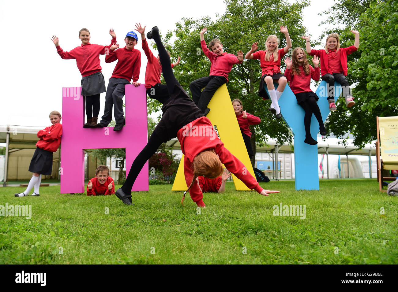 Hay on Wye, Wales, UK. 26. Mai 2016.  Der Eröffnungstag der Hay Festival 2016 und der Schülerinnen und Schüler aus Burghill Gemeinsc Akademie in Herefordshire viel Spaß mit dem riesigen Heu-Zeichen auf dem Festivalgelände Foto Credit: Keith Morris/Alamy Live-Nachrichten Stockfoto