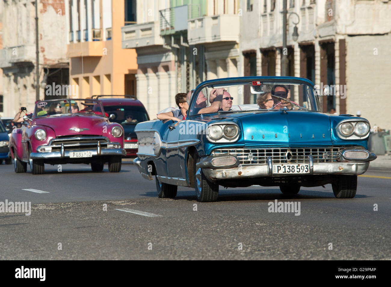 Ein 1958 Pontiac Super Chief (blaues Auto) und eine 1950 Chevrolet Bel Air (lila Auto) Reisen entlang der Malecón in Havanna, Kuba. Stockfoto