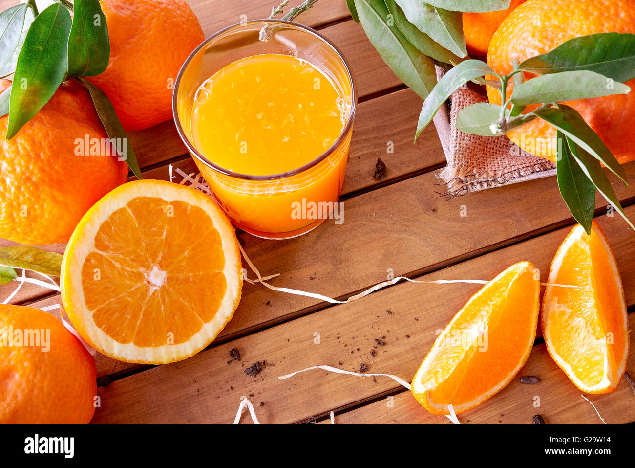 Glas Orangensaft auf einem Holztisch mit Orangen und orange Abschnitte. Horizontale Komposition. Ansicht von oben Stockfoto