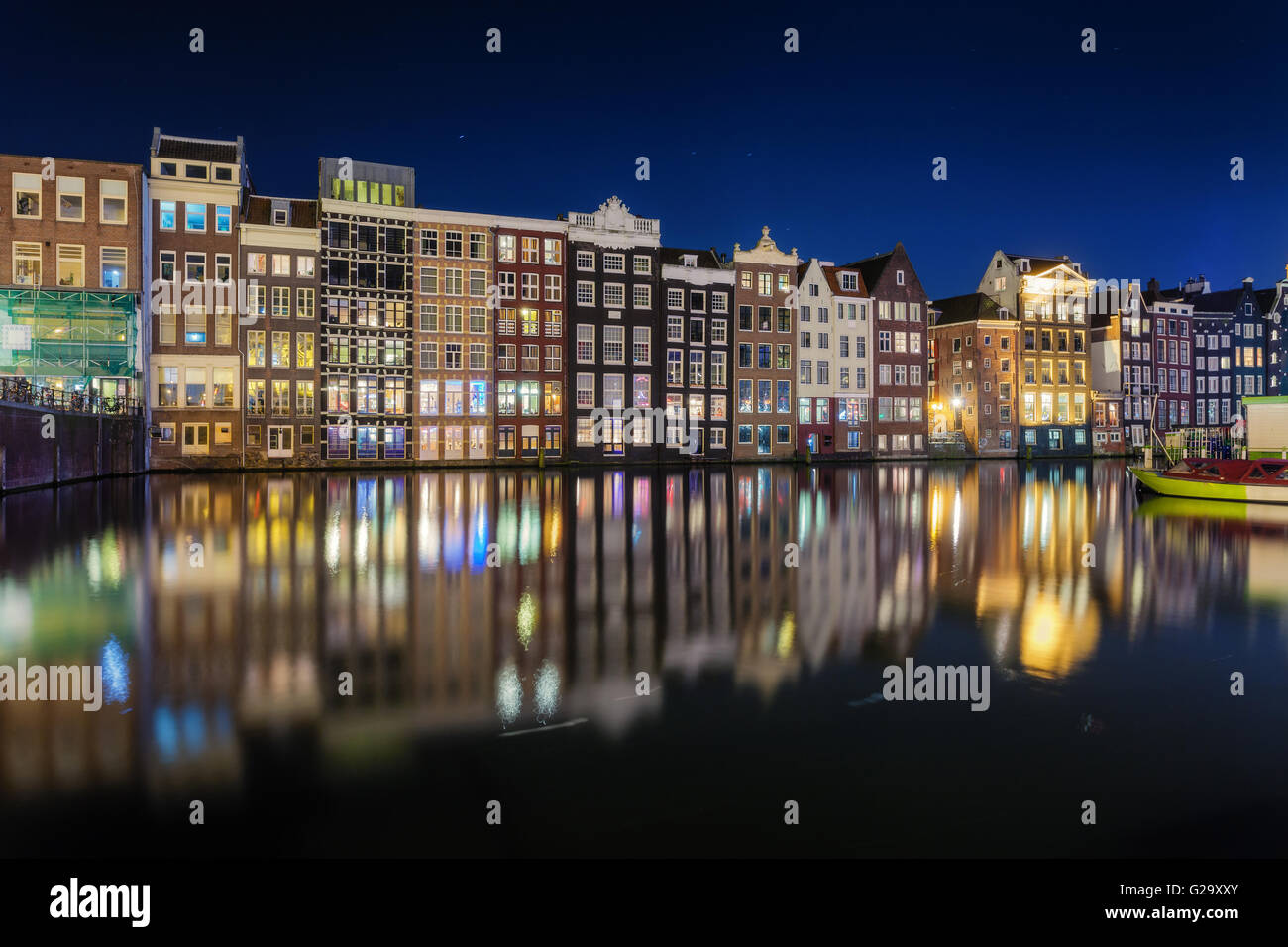 Schöne traditionelle alte Häuser in der Nacht in Amsterdam, Niederlande. Stadtbild mit reflektierten Stadtgebäude in Wasser mit blau Stockfoto