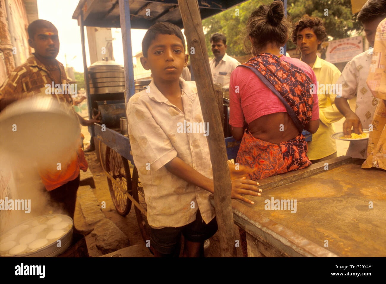 Ein kleiner Junge steht vor einer Straße Imbiss-Stand, Mahabalipuram, Tamil Nadu, Indien. Stockfoto