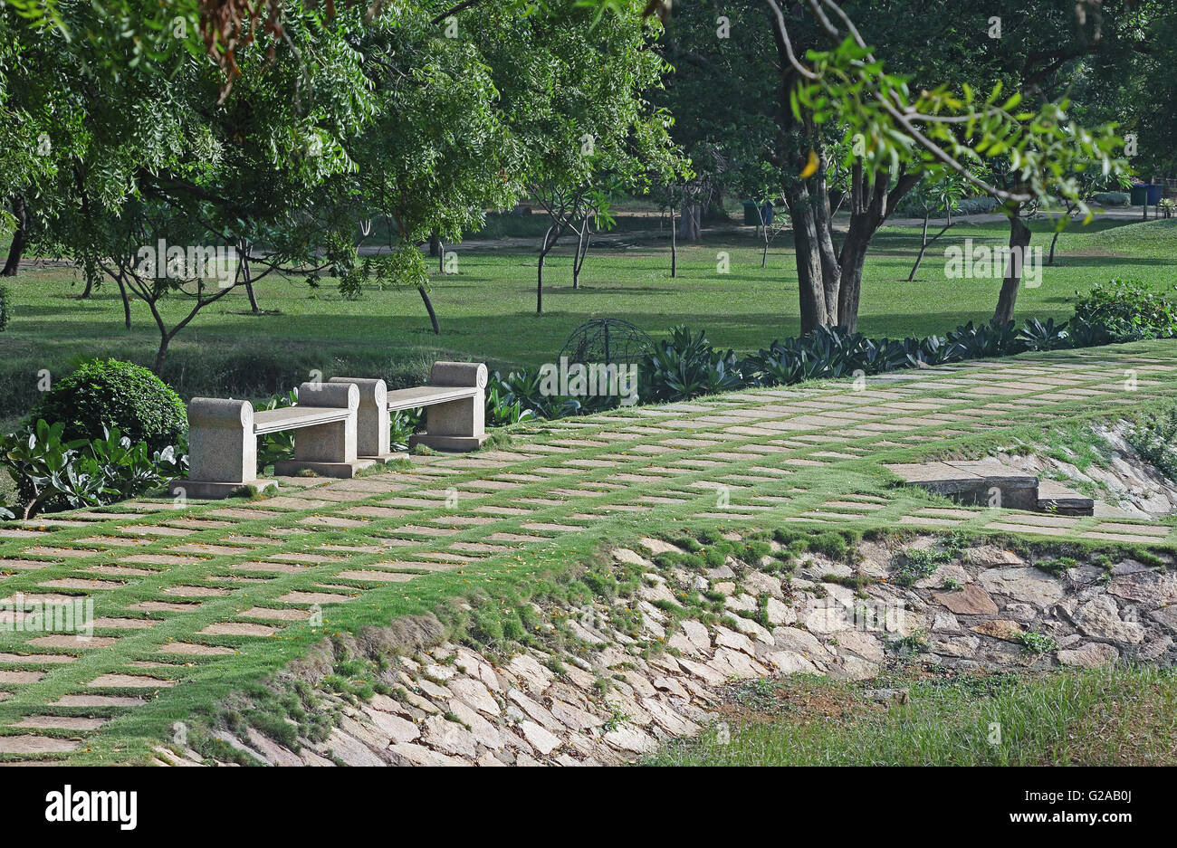 Zwei steinerne park Bänke entlang eines Weges mit grobem Granit Steinplatten gepflastert Stockfoto