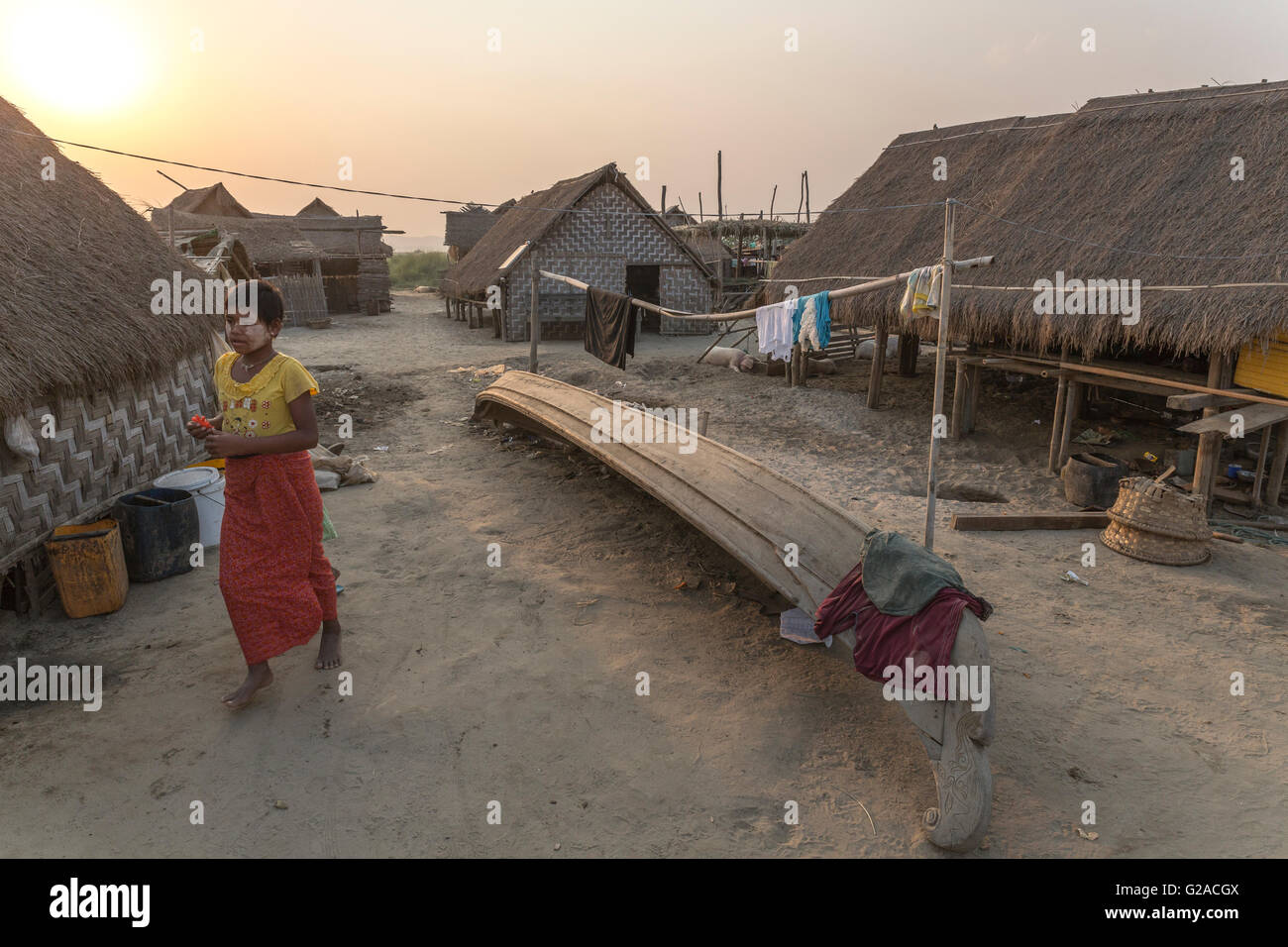 Junge Mädchen, die zu Fuß in ein typisches Dorf mit Häusern und Booten der Fischer, Mandalay, Myanmar, Burma, Südasien, Asien Stockfoto