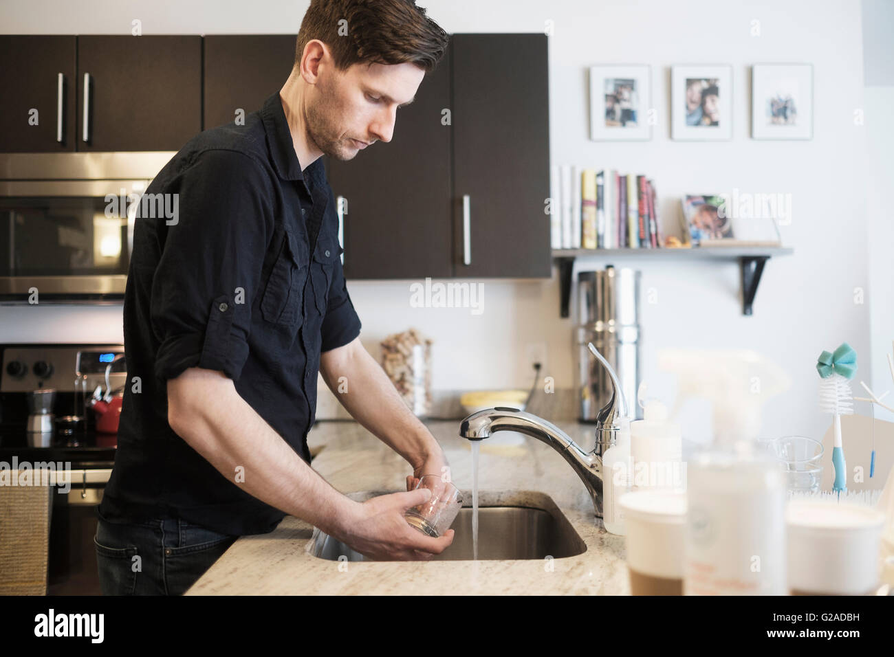 Mann Waschen Trinkglas in Küche Stockfoto