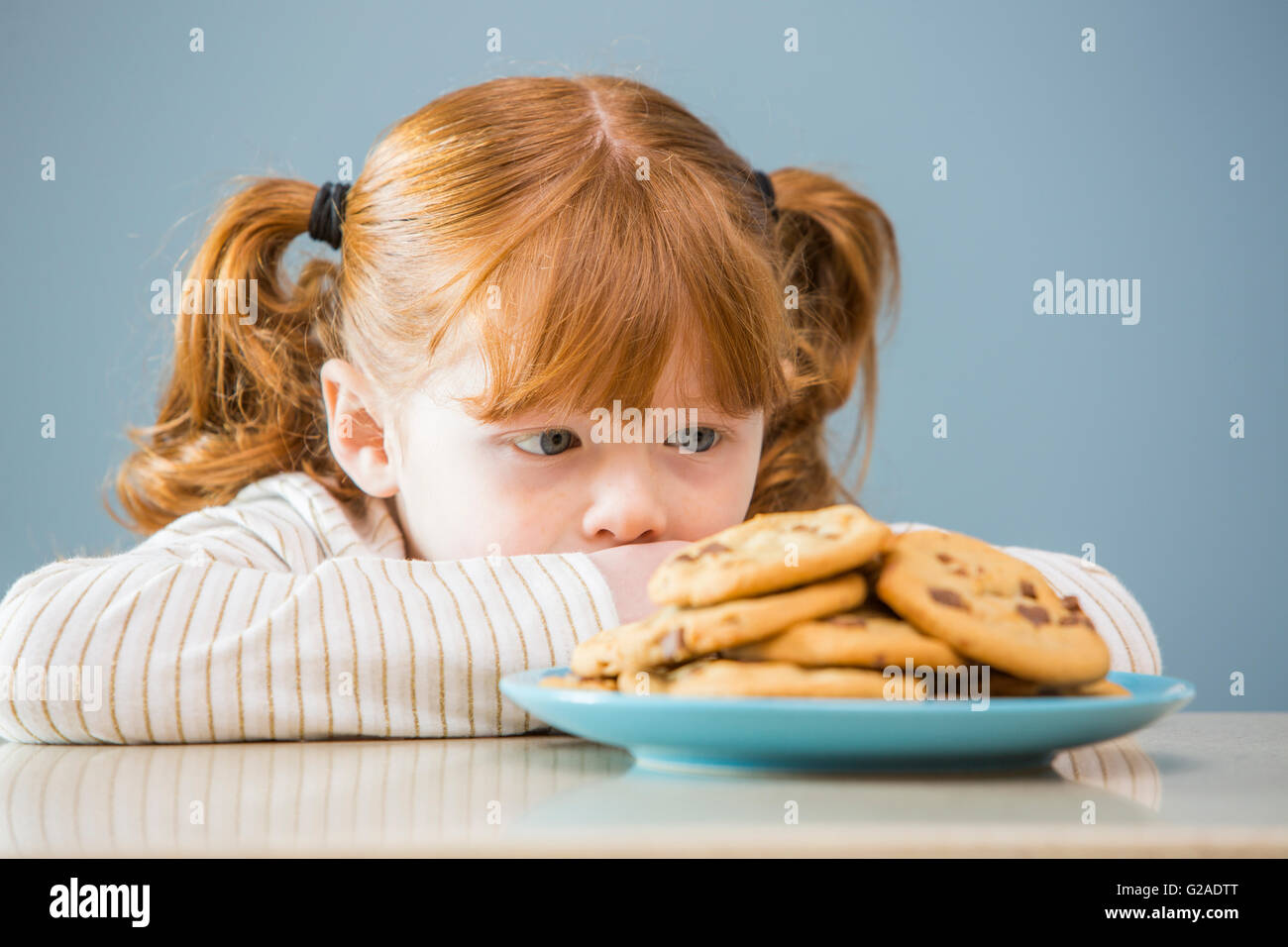 Mädchen (4 -5) auf der Suche auf Teller mit Keksen Stockfoto
