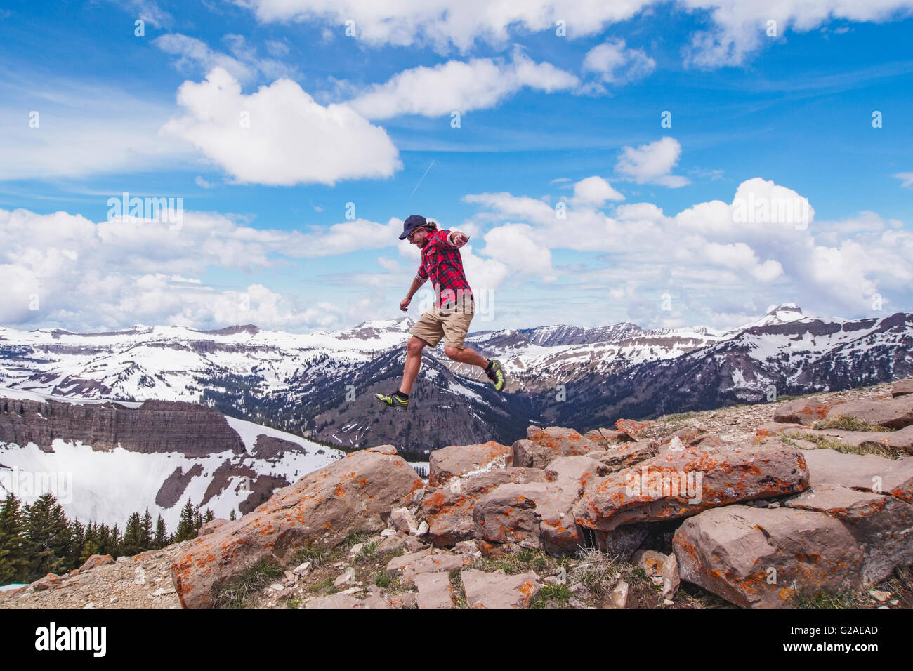 Mitte erwachsenen Mann springt über Felsen in Bergen Stockfoto