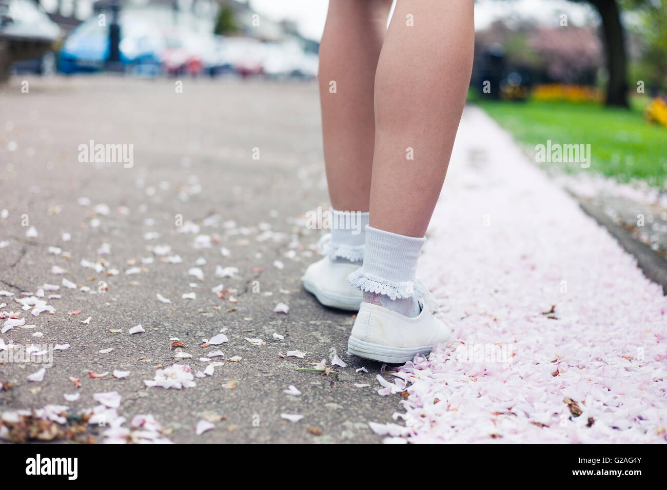 Die Beine und Füße einer jungen Frau wie sie unter die Kirschblüte in einem Park im Frühjahr Fuß ist Stockfoto