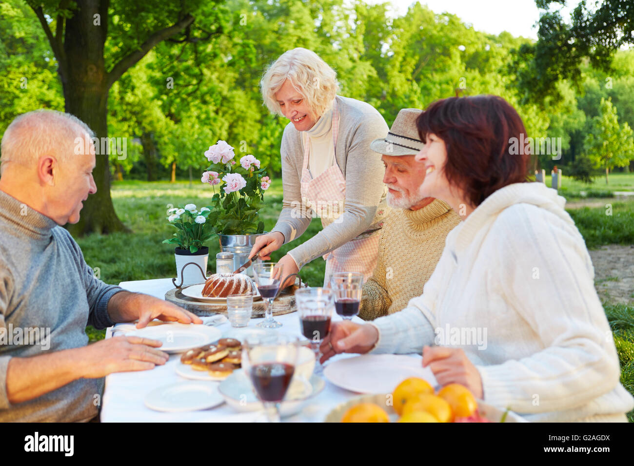 Familie mit älteren Menschen essen Kuchen auf Geburtstagsparty in einem Garten Stockfoto