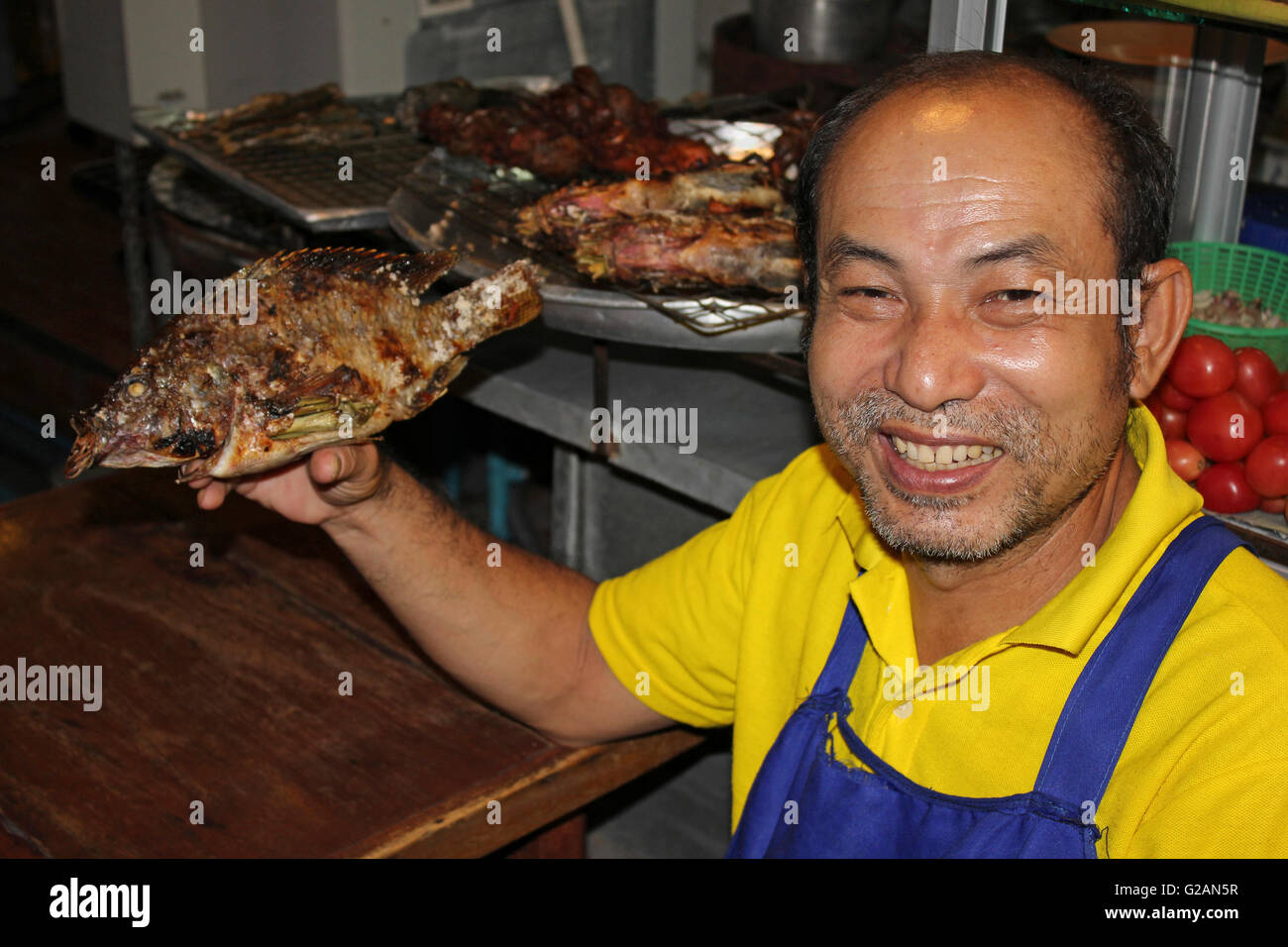 Thai Mann halten gekochte Fische zum Verkauf am Nachtmarkt Stockfoto
