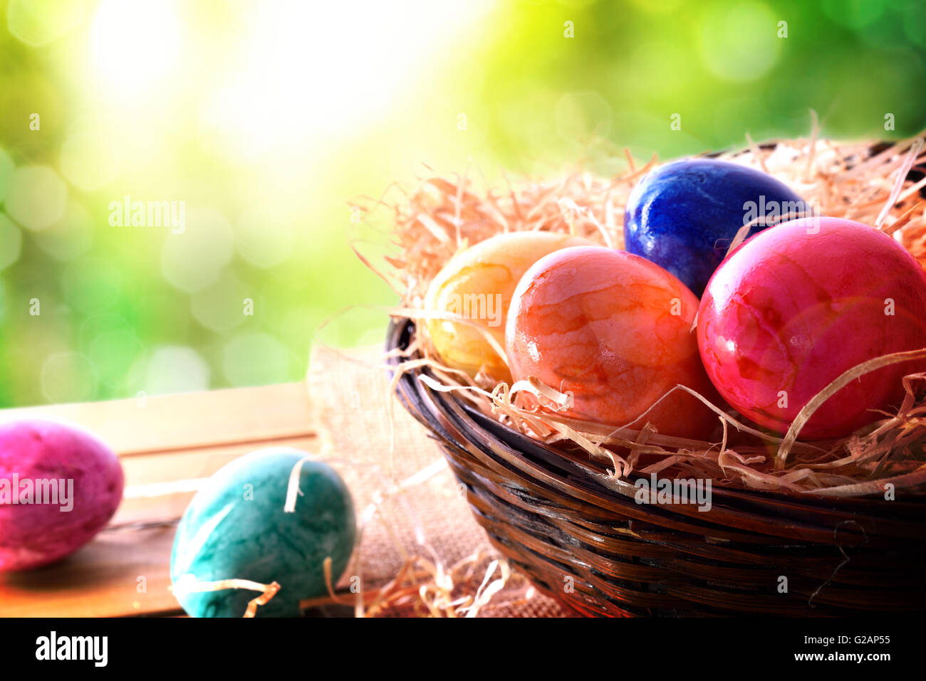 Ostereier auf einem Holztisch und einen Korb auf dem Gebiet. Horizontale Komposition. Erhöhten Blick Stockfoto