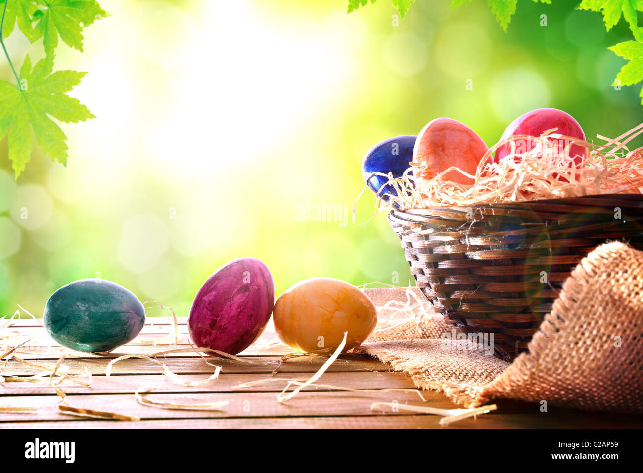 Ostereier auf einem Holztisch und einen Korb auf dem Gebiet. Horizontale Komposition. Vorderansicht Stockfoto