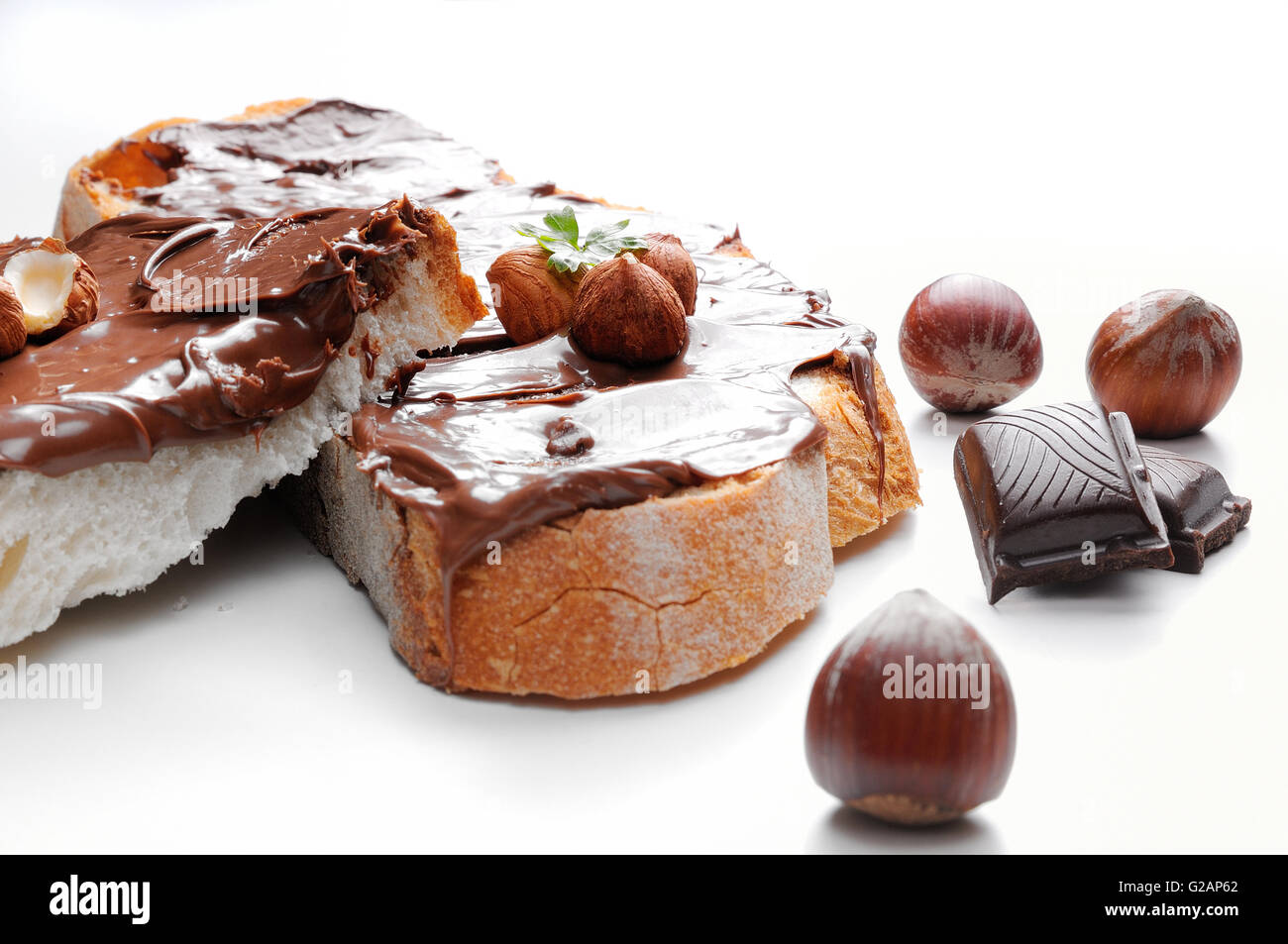 Zwei Scheiben Brot mit Schokoladencreme und Haselnüssen weiße isoliert Vorderansicht. Haselnuss und Schokolade Dekoration. Stockfoto